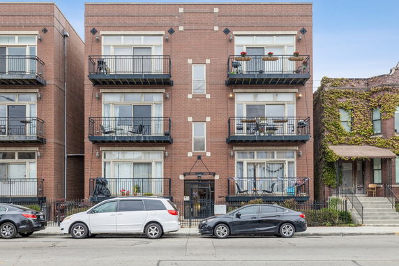 Front view of a three-story brick apartment building with balconies.