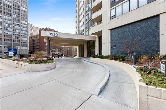 Front view of a multi-story building with a covered entrance and driveway.