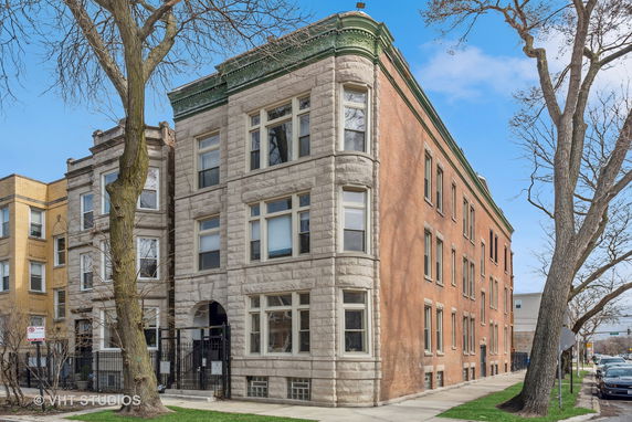Front view of a multi-story residential building with a mix of stone and brick exterior.