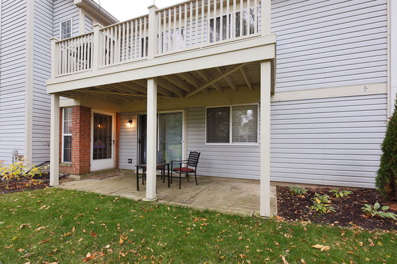 Rear view of a two-story house with a patio and a balcony.