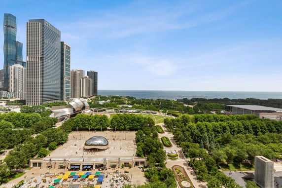 Panoramic view of a cityscape with tall modern buildings and a body of water in the background.
