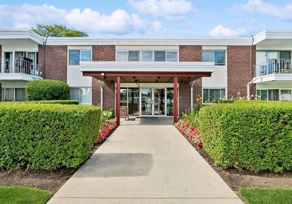 Front view of a two-story brick building with a central entrance and covered walkway.