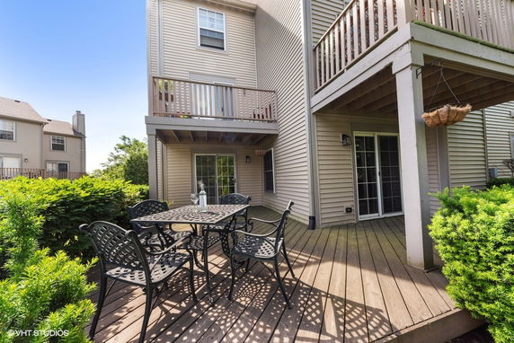 Back view of a house with a wooden deck and patio furniture.