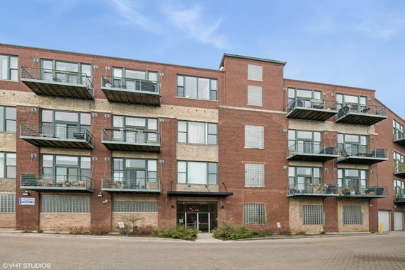 Front view of a multi-story brick apartment building with balconies.