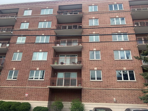 Front view of a multi-story brick apartment building with balconies.