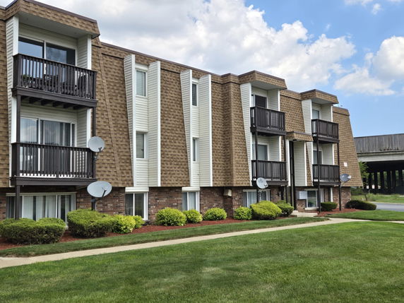 Front view of a multi-story apartment building with balconies and satellite dishes.