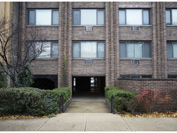 Front view of a multi-story brick building with an arched entrance.