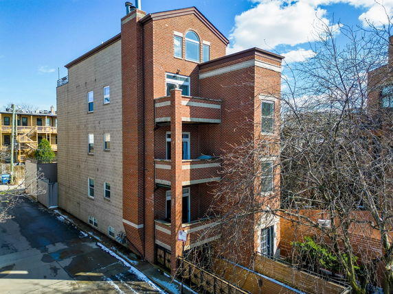 Side view of a tall, brick residential building with multiple balconies.