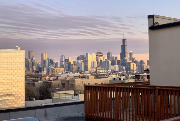 Rooftop view with city skyline in the distance during sunset.