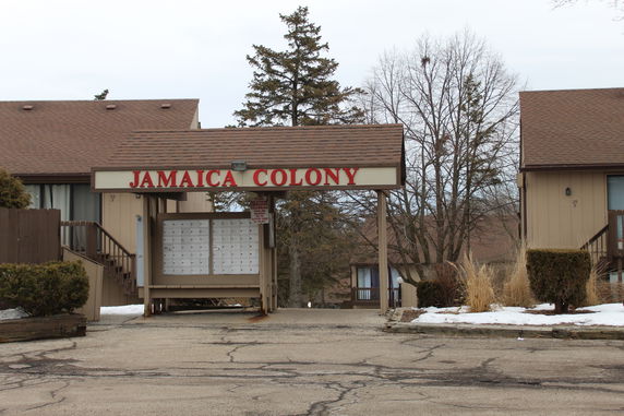 Front view of residential buildings in a complex with sign reading 'Jamaica Colony'.
