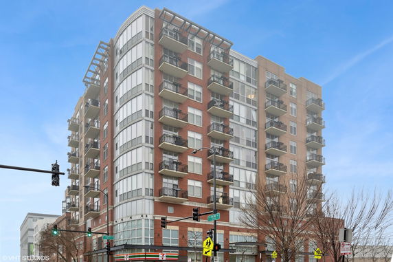 Front view of a multi-story apartment building with balconies and large windows.