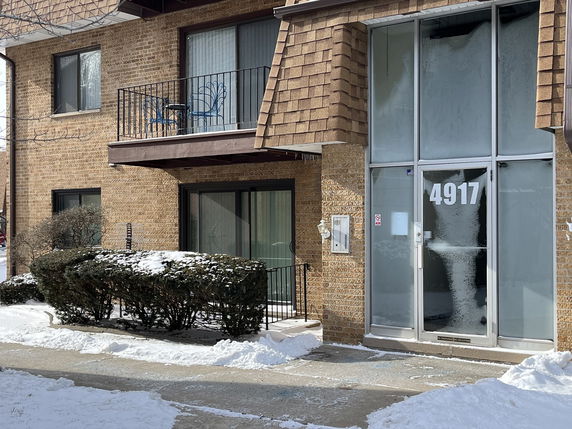 Front view of a brick apartment building with a balcony and a large entry door marked with the number 4917.