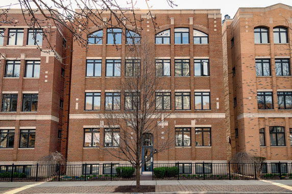 Front view of a multi-story brick building with large windows.