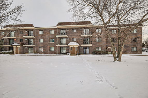 Front view of a multi-story brick apartment building with balconies.