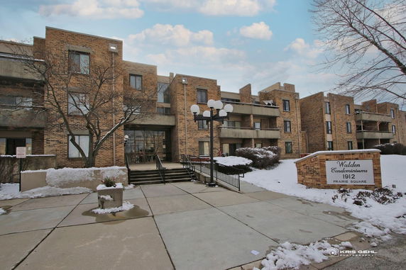 Front view of a brick condominium building with multiple balconies and a central entrance.