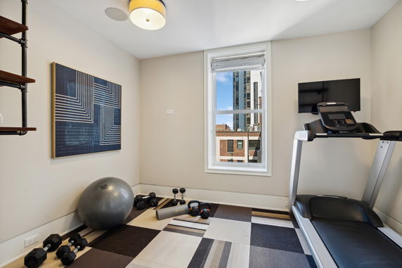 Interior view of a gym room with a treadmill and exercise equipment.