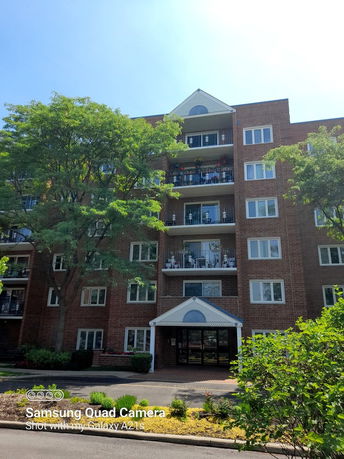 Front view of a multi-story brick apartment building with balconies.