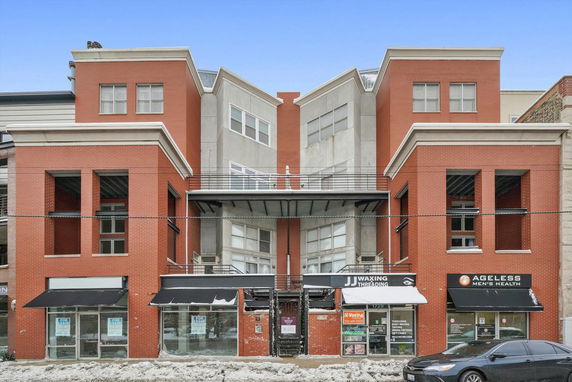 Front view of a multi-story commercial building with large windows and brick facade.