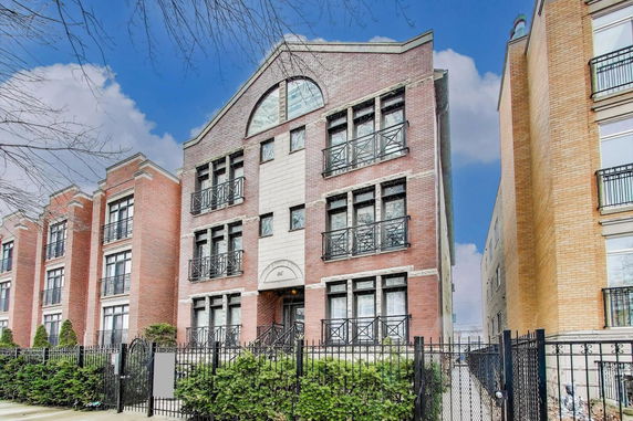 Front view of a multi-story brick apartment building with balconies.