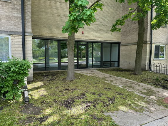 Front view of a brick building with large windows and a concrete walkway.