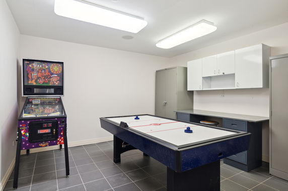 Room with air hockey table and pinball machine.