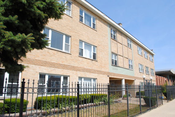 Front view of a multi-story brick building with a fence.