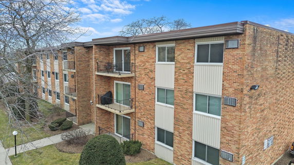 Front view of a multi-story brick apartment building with balconies.