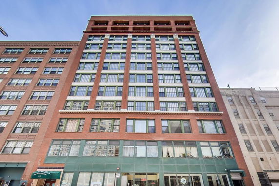 Front view of a multi-story brick building with large windows.