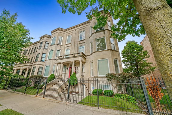Front view of a multi-story residential building with large windows and a gated entrance.