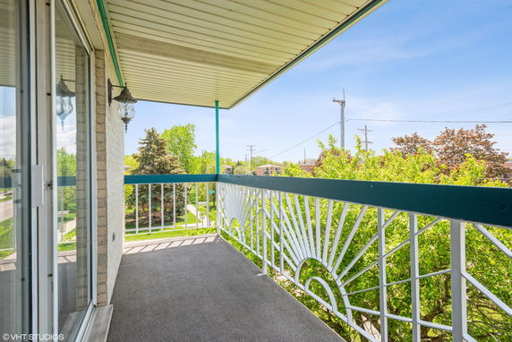 Balcony view with decorative railing overlooking trees and neighborhood.