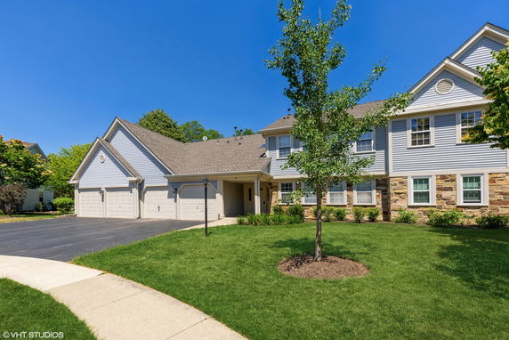 Front view of a two-story house with a three-car garage and stone accents.