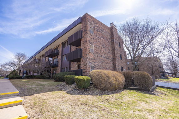 Front view of a brick apartment building with balconies.