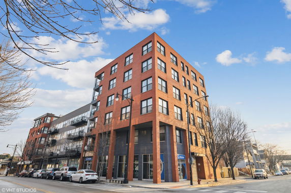 Front view of a multi-story brick building with large windows.