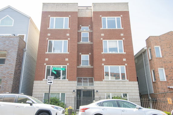 Front view of a brick apartment building with multiple floors and large windows.