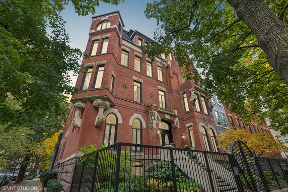 Front view of a large multi-story brick building with arched windows and decorative stone elements.