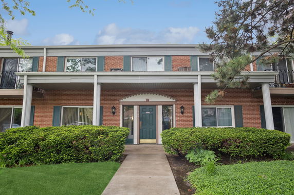 Front view of a two-story brick building with green shutters and a central entrance.