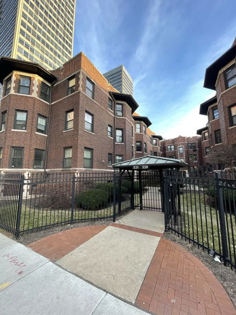 Front view of a brick multi-story apartment building with a gated entrance.