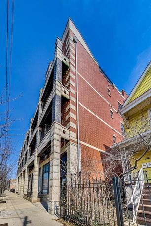 Front view of a multi-story brick building with balconies and large windows.