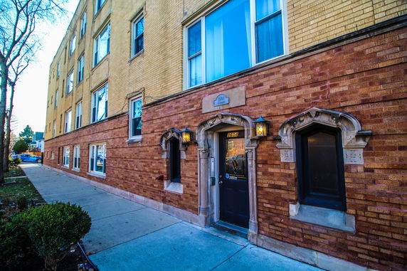 Front view of a brick apartment building with decorative windows and entry.