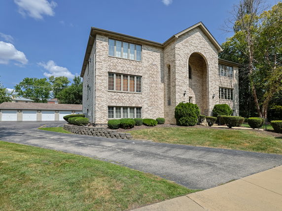 Front view of a two-story brick building with large windows and an arched entrance.