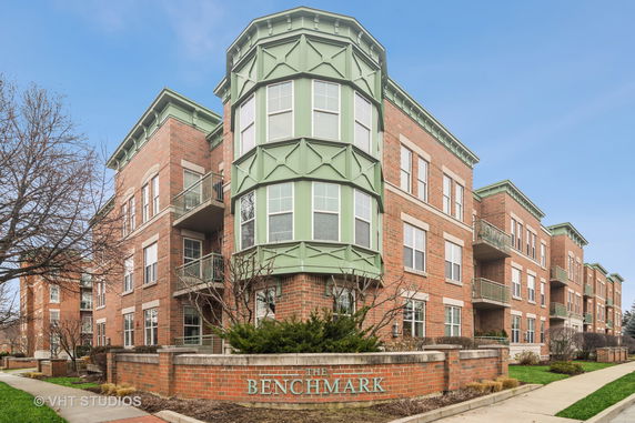 Front view of a multi-story residential building with brick facade and green trim.