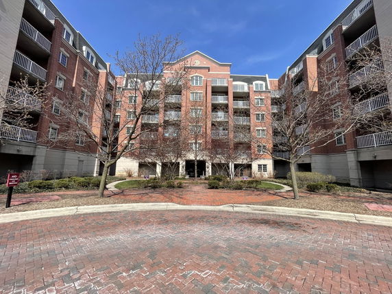 Front view of a multi-story brick residential building with balconies.