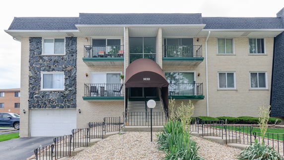 Front view of a multi-story apartment building with a central entrance and balconies.