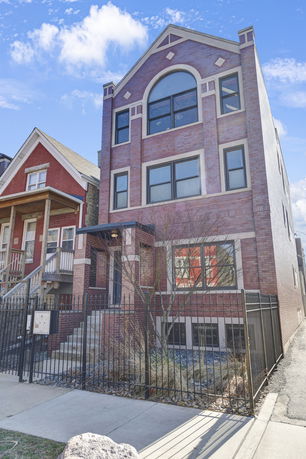 Front view of a multi-story brick house with a gated entrance.