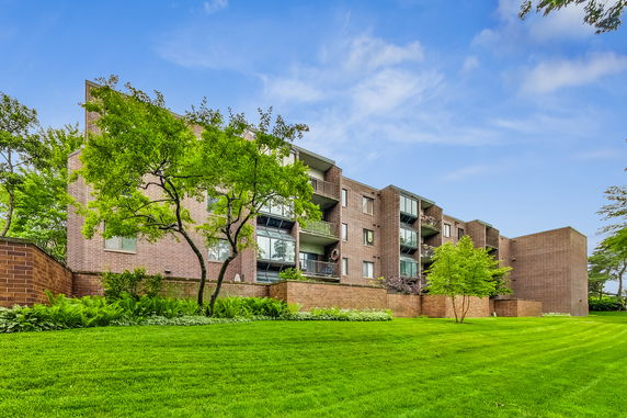 Front view of a multi-story brick apartment building with balconies.