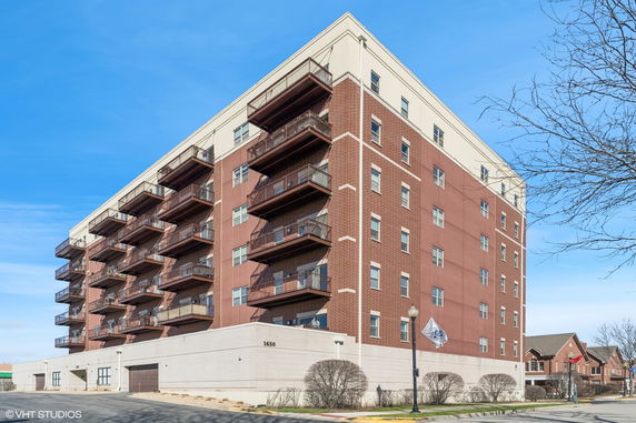 Front view of a multi-story brick apartment building with balconies.