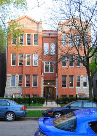 Front view of a multi-story brick building with large windows.