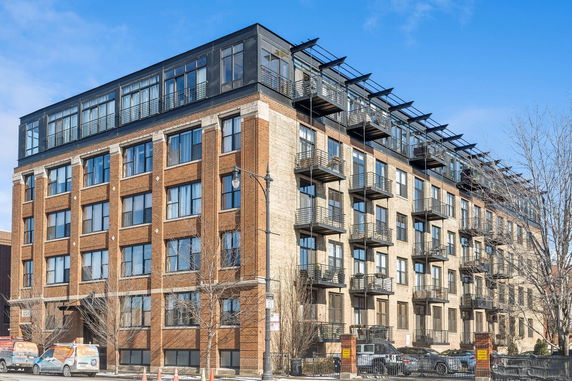 Front view of a multi-story apartment building with brick facade and balconies.