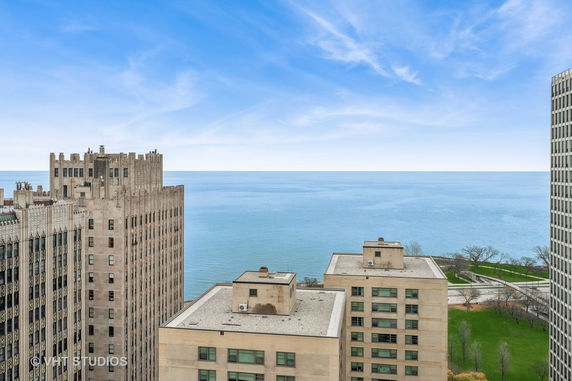 Panoramic view of a lake as seen from a tall building, with other buildings in the foreground.