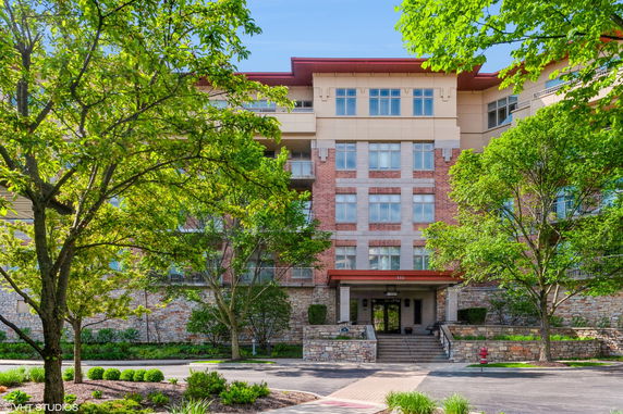 Front view of a multi-story brick and stone building with large windows and an entrance canopy.